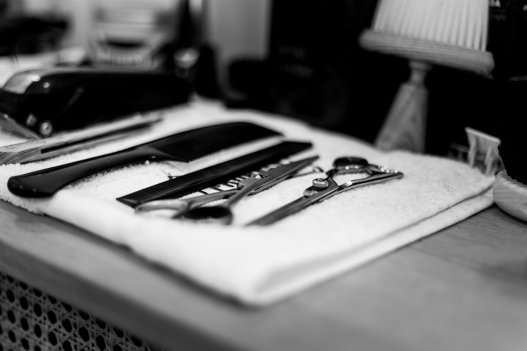 Barber scissors and combs laid out on a towel, black and white
