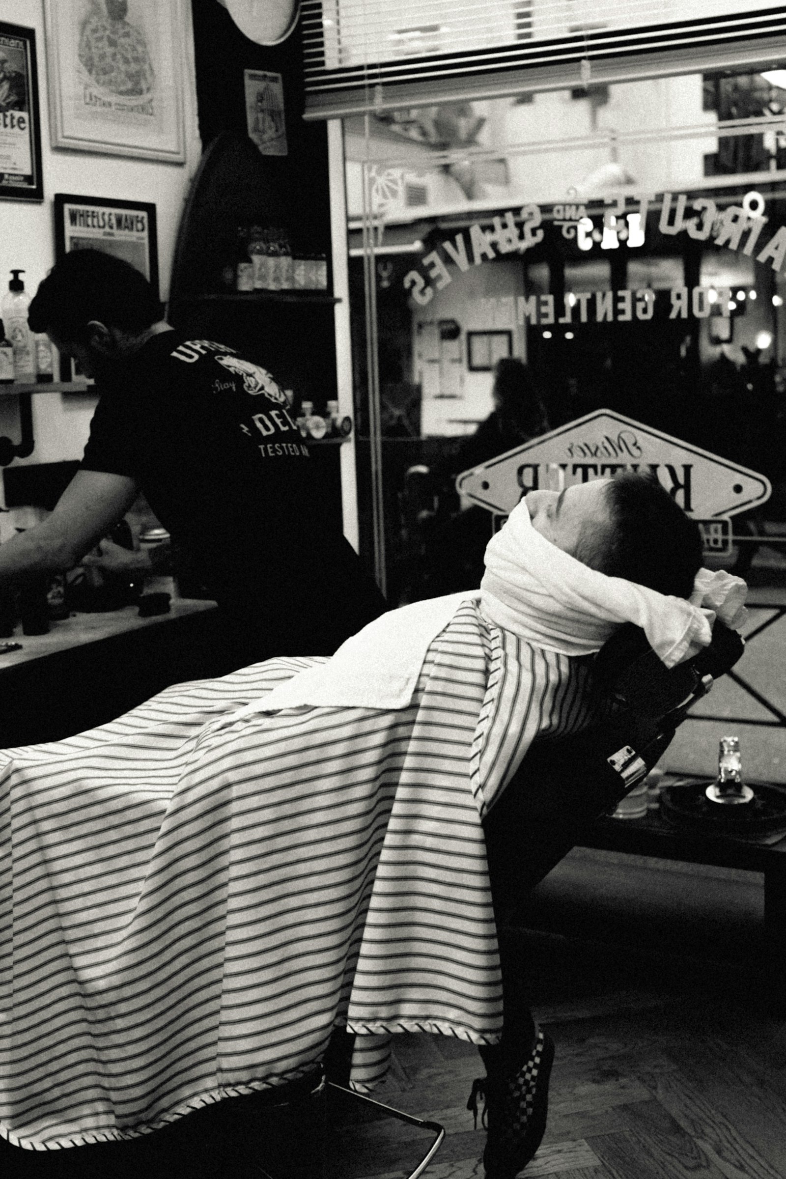 Client reclined for a shave in a classic barbershop, black and white